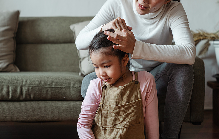 Eine Mutter bindet ihrer Tochter die Haare