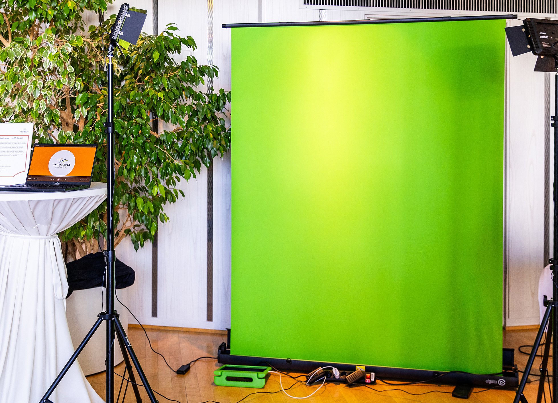 Ein aufgebauter Greenscreen mit einem Licht-Set und einem Laptop.