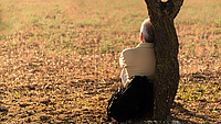 Von hinten zu sehen ein Mann lehnt an mit seinem Rücken an einem Baum und schaut in die Landschaft  Quelle: josealbefotos auf Pixabay