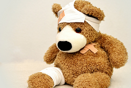 Ein Plüschteddybär, der am Kopf und am rechten Bein bandagiert ist.