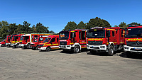Mehrere Feuerwehrfahrzeuge stehen auf einem großen Platz unter freiem Himmel.
