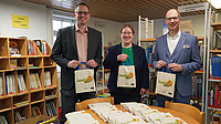 Bürgermeister Raik Noll, Felicitas Wahl und Landrat Jan Weckler zeigen die Lesestart-Tüten.