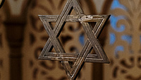 Ein Davidstern hängt in einem Raum. Im Hintergrund sind geschnitzte Raumteiler zu sehen.