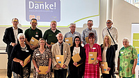 Zwölf Menschen stehen vor einer Wand, auf der Danke steht.