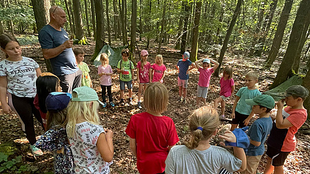 Kinder bilden einen Kreis, stehen im Wald